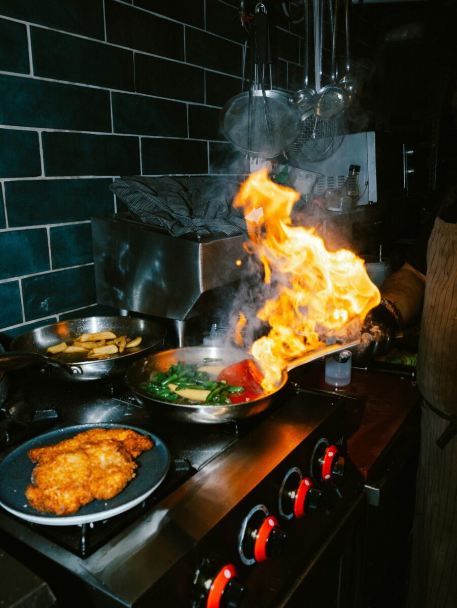 Chef flambeing food in a pan on stove Chef flambeing food in a pan on stove
